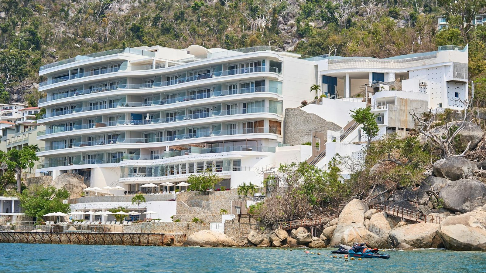 Luxurious beachfront resort nestled against a hillside with scenic water views.