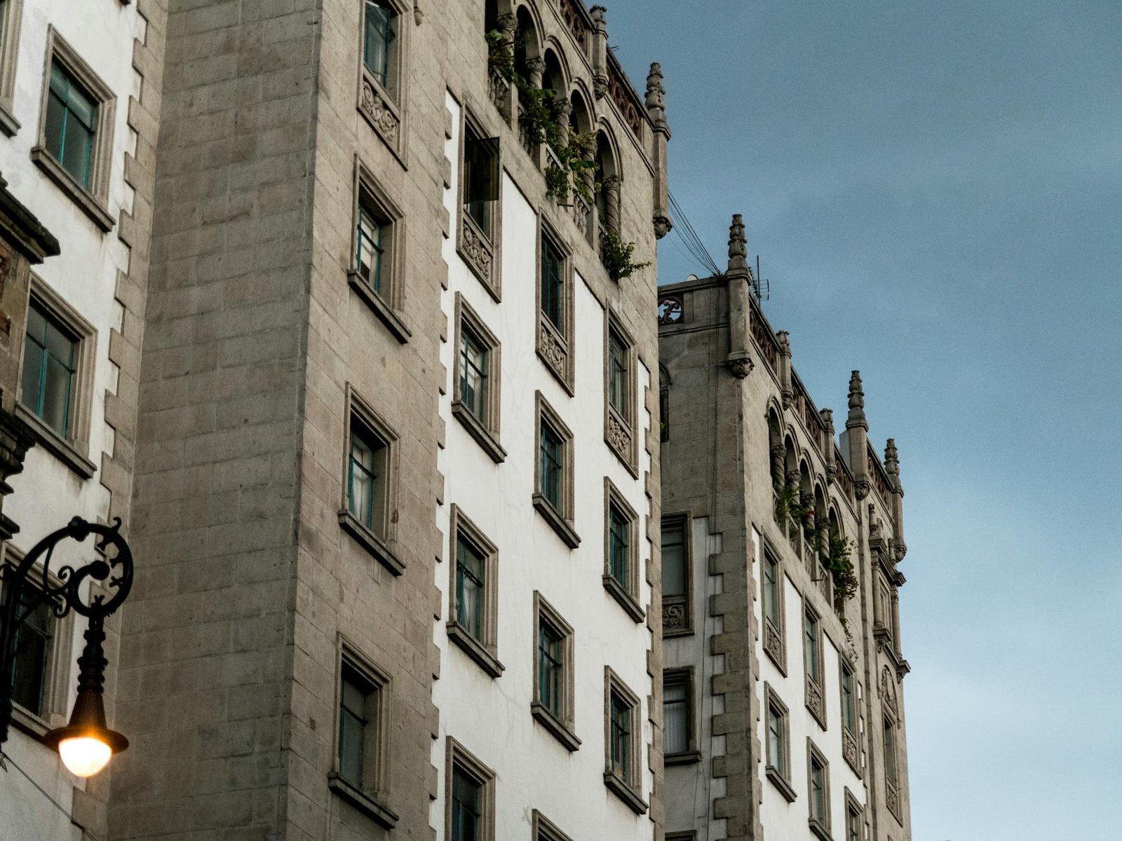 Detailed view of a historic building's facade with ornate windows against a blue sky in an urban setting.