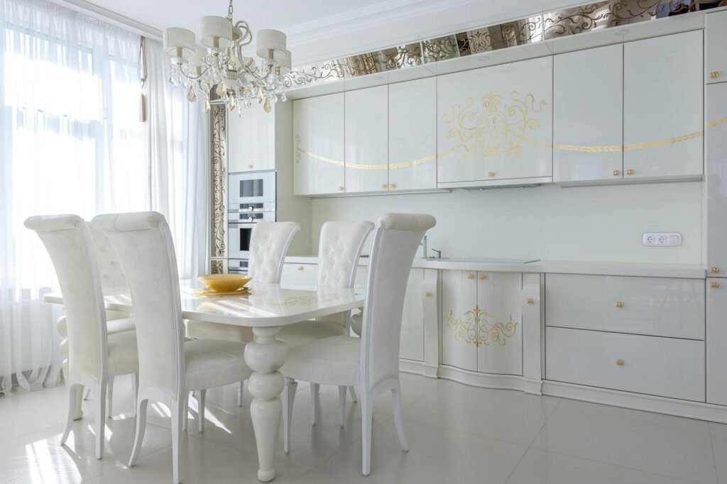 Light kitchen interior with white furniture with golden print dining table and chairs in classic style